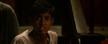 Movie still from “Extraction” (2020), directed by Sam Hargrave – A young man is looking at the camera; Close Up shot, High angle