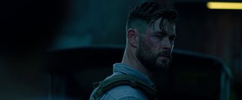 Movie still from “Extraction” (2020), directed by Sam Hargrave – A person with a beard; Close Up shot, Over the shoulder angle