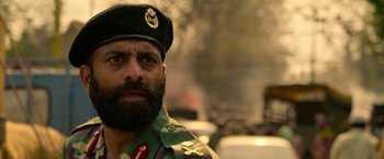 Movie still from “Extraction” (2020), directed by Sam Hargrave – A man with a beard wearing a military uniform; Close Up shot, Low angle