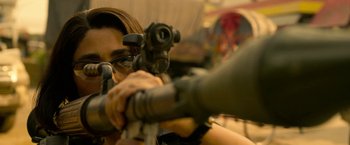 Movie still from “Extraction” (2020), directed by Sam Hargrave – A woman is holding a rifle and aiming it; Close Up shot, Low angle