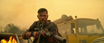 Movie still from “Extraction” (2020), directed by Sam Hargrave – A man holding a gun while standing next to a bus; Medium shot, Over the shoulder angle