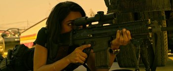 Movie still from “Extraction” (2020), directed by Sam Hargrave – A woman is holding a rifle and aiming it; Close Up shot, Low angle