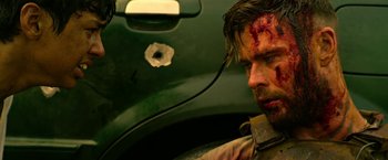Movie still from “Extraction” (2020), directed by Sam Hargrave – A person with blood on his face; Close Up shot, Over the shoulder angle
