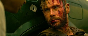 Movie still from “Extraction” (2020), directed by Sam Hargrave – A person with blood on his face; Close Up shot, Over the shoulder angle