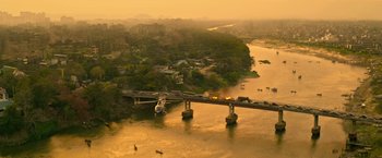 Movie still from “Extraction” (2020), directed by Sam Hargrave – An aerial view of a bridge over a body of water; Extreme Wide shot, High angle