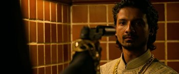 Movie still from “Extraction” (2020), directed by Sam Hargrave – A man with a beard is holding a camera; Close Up shot, Low angle