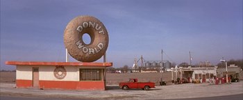 Movie still from “Mars Attacks!” (1996), directed by Tim Burton – A red truck parked in front of a donut shop; Extreme Wide shot, High angle
