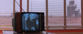 Movie still from “Mars Attacks!” (1996), directed by Tim Burton – An old tv with a picture of a man in a suit; Medium shot, Over the shoulder angle