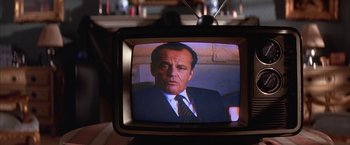 Movie still from “Mars Attacks!” (1996), directed by Tim Burton – A television with a picture of a man in a suit; Close Up shot, Over the shoulder angle