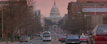 Movie still from “Mars Attacks!” (1996), directed by Tim Burton – A bus driving down a street past a large building; Extreme Wide shot, Low angle