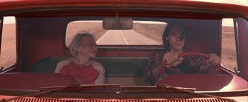 Movie still from “Mars Attacks!” (1996), directed by Tim Burton – Two people sitting in the back seat of a car; Medium shot, Over the shoulder angle