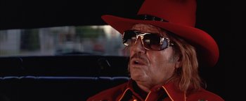 Movie still from “Mars Attacks!” (1996), directed by Tim Burton – An older man wearing a red hat and sunglasses; Close Up shot, Low angle