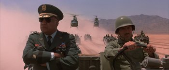 Movie still from “Mars Attacks!” (1996), directed by Tim Burton – Two men in military uniforms are looking out over the desert; Medium shot, Low angle