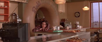 Movie still from “Mars Attacks!” (1996), directed by Tim Burton – A man sitting at a table in a donut shop; Medium shot, Low angle