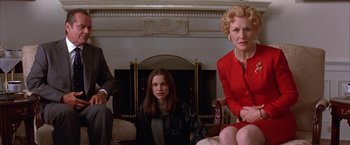 Movie still from “Mars Attacks!” (1996), directed by Tim Burton – Two women and a man sitting in a living room next to a fire place; Medium shot, Low angle