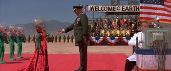 Movie still from “Mars Attacks!” (1996), directed by Tim Burton – A man in a military uniform standing on a red carpet; Extreme Wide shot, High angle