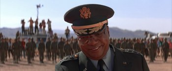 Movie still from “Mars Attacks!” (1996), directed by Tim Burton – A man in a military uniform is smiling for the camera; Close Up shot, Low angle