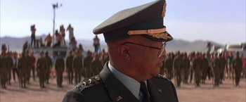 Movie still from “Mars Attacks!” (1996), directed by Tim Burton – A man in a military uniform is standing in front of a group of people; Close Up shot, Low angle