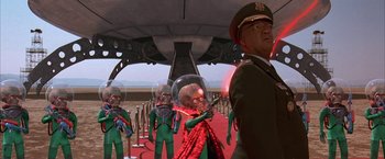 Movie still from “Mars Attacks!” (1996), directed by Tim Burton – A group of men in green suits and helmets; Wide shot, Low angle