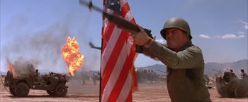Movie still from “Mars Attacks!” (1996), directed by Tim Burton – An american flag being held up by a man holding a rifle; Medium shot, Low angle