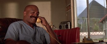 Movie still from “Mars Attacks!” (1996), directed by Tim Burton – A man sitting in a booth talking on a phone; Close Up shot, Low angle