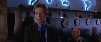 Movie still from “Mars Attacks!” (1996), directed by Tim Burton – A man wearing a suit and tie in front of a clock; Medium shot, Low angle