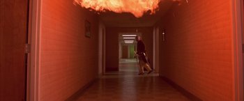 Movie still from “Mars Attacks!” (1996), directed by Tim Burton – A man is walking down a hallway with a fire coming out of the ceiling; Wide shot, Low angle