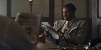 Movie still from “Marshall” (2017), directed by Reginald Hudlin – A man sitting at a table reading a newspaper; Medium shot, Over the shoulder angle
