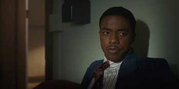 Movie still from “Marshall” (2017), directed by Reginald Hudlin – A man wearing a suit and tie sitting in front of a wall; Close Up shot, Over the shoulder angle