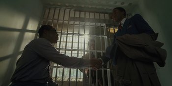 Movie still from “Marshall” (2017), directed by Reginald Hudlin – Two men shake hands in front of a jail cell; Medium shot, High angle