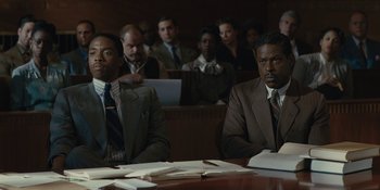 Movie still from “Marshall” (2017), directed by Reginald Hudlin – A couple of men sitting at a table in a courtroom; Medium shot, Over the shoulder angle