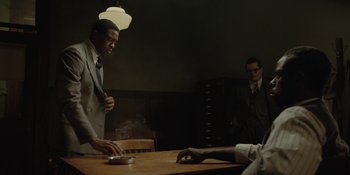 Movie still from “Marshall” (2017), directed by Reginald Hudlin – Two men in suits and ties sitting at a wooden table; Medium shot, Over the shoulder angle