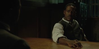 Movie still from “Marshall” (2017), directed by Reginald Hudlin – A man sitting at a wooden table in front of a computer; Close Up shot, Over the shoulder angle
