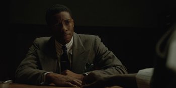 Movie still from “Marshall” (2017), directed by Reginald Hudlin – A man sitting at a table in front of a wall; Close Up shot, Over the shoulder angle