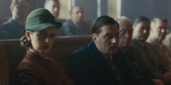 Movie still from “Marshall” (2017), directed by Reginald Hudlin – A man and a woman sitting next to each other in front of other men; Medium shot, Over the shoulder angle