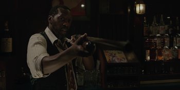 Movie still from “Marshall” (2017), directed by Reginald Hudlin – A man holding a baseball bat in a room; Medium shot, Over the shoulder angle