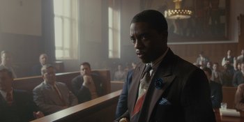 Movie still from “Marshall” (2017), directed by Reginald Hudlin – A man wearing a suit and tie in a courtroom; Medium shot, Over the shoulder angle