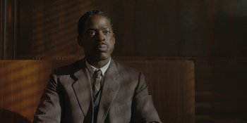 Movie still from “Marshall” (2017), directed by Reginald Hudlin – A man wearing a suit and tie in front of a wooden wall; Close Up shot, Low angle