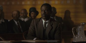 Movie still from “Marshall” (2017), directed by Reginald Hudlin – A man in a brown suit sitting at a table; Medium shot, Low angle