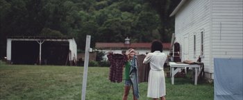 Movie still from “Martha Marcy May Marlene” (2011), directed by Sean Durkin – A woman and a child hanging clothes on a clothes line; Wide shot, Over the shoulder angle