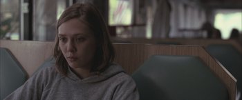 Movie still from “Martha Marcy May Marlene” (2011), directed by Sean Durkin – A young woman sitting in a chair in front of a window; Close Up shot, Over the shoulder angle