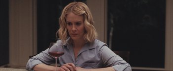 Movie still from “Martha Marcy May Marlene” (2011), directed by Sean Durkin – A woman sitting at a table holding a glass of wine; Close Up shot, Over the shoulder angle