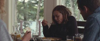 Movie still from “Martha Marcy May Marlene” (2011), directed by Sean Durkin – A woman is sitting at a table eating food; Medium shot, Over the shoulder angle