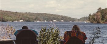 Movie still from “Martha Marcy May Marlene” (2011), directed by Sean Durkin – Two people sitting in lawn chairs looking out at the water; Extreme Wide shot, Over the shoulder angle