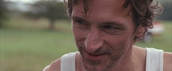 Movie still from “Martha Marcy May Marlene” (2011), directed by Sean Durkin – A man's face in a field; Close Up shot, Over the shoulder angle