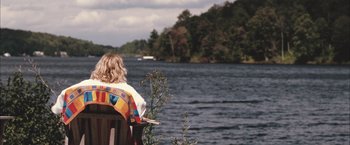 Movie still from “Martha Marcy May Marlene” (2011), directed by Sean Durkin – A woman sitting on a chair looking out at a body of water; Extreme Wide shot, High angle
