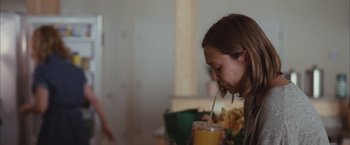 Movie still from “Martha Marcy May Marlene” (2011), directed by Sean Durkin – A woman drinking a drink from a glass; Medium shot, Over the shoulder angle