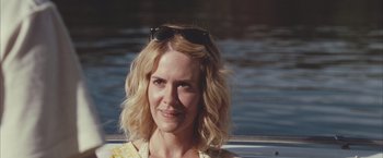 Movie still from “Martha Marcy May Marlene” (2011), directed by Sean Durkin – A woman with blonde curly hair wearing sunglasses; Close Up shot, Over the shoulder angle