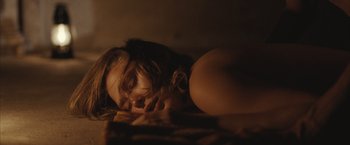 Movie still from “Martha Marcy May Marlene” (2011), directed by Sean Durkin – A woman laying on the ground with her eyes closed; Close Up shot, High angle