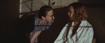 Movie still from “Martha Marcy May Marlene” (2011), directed by Sean Durkin – Two women are talking in a dark room; Medium shot, Over the shoulder angle